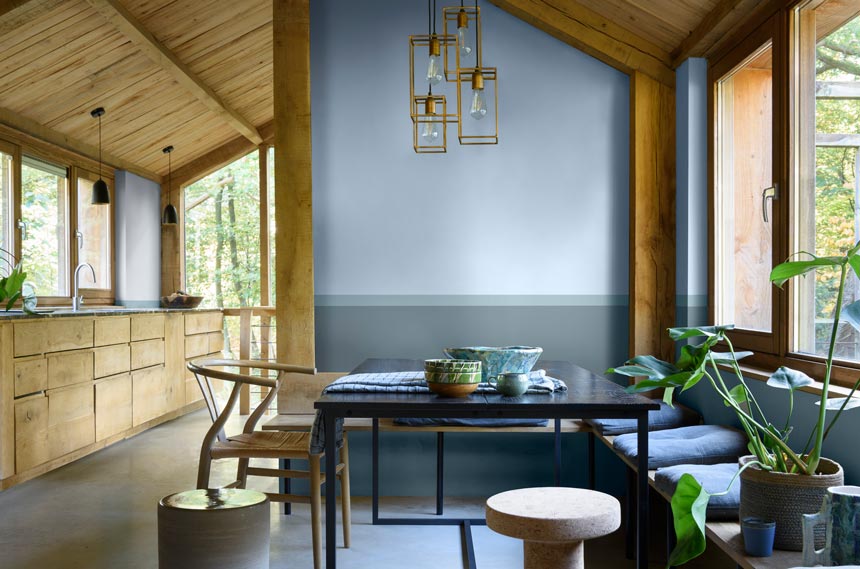 A very bright rustic galley kitchen and a open plan dining space with an accent wall featuring Dulux Bright Skies and two other colors from the Greenhouse palette. Image credit: Dulux.