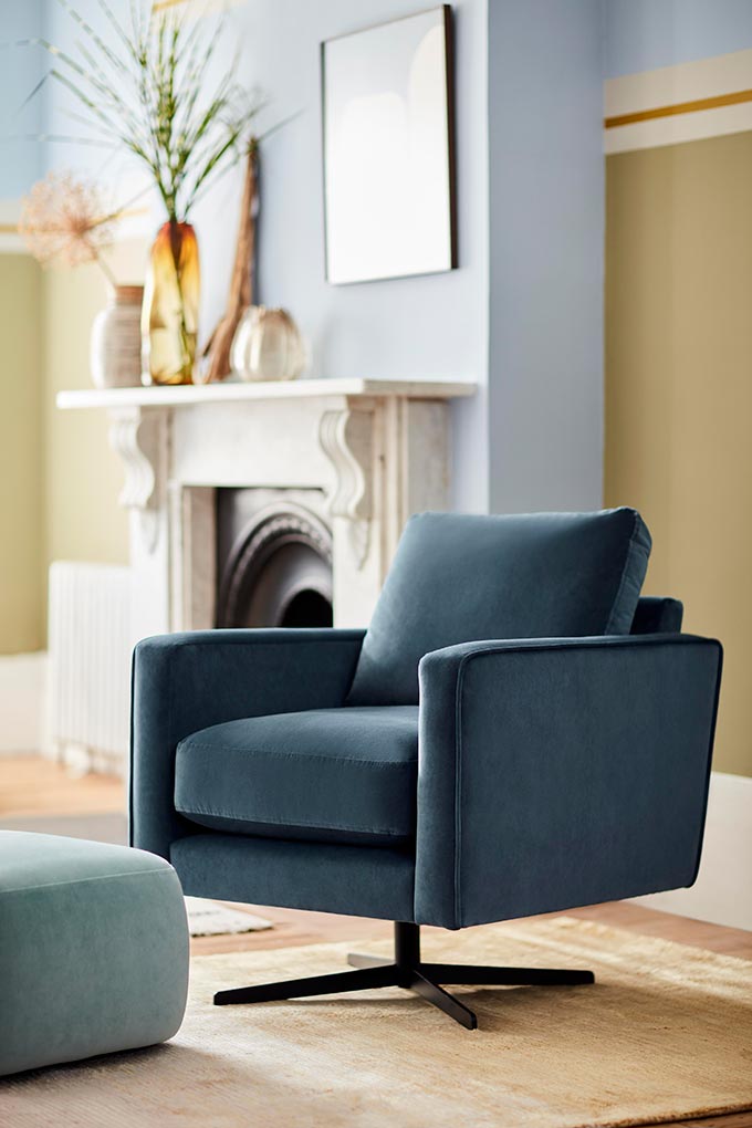 A lifestyle image of a velvet swivel chair in a beautiful color - Denim Drift by Dulux. It compliments nicely the Blue Skies color by Dulux featured on the walls in the background. Image: DFS CO. PLC.