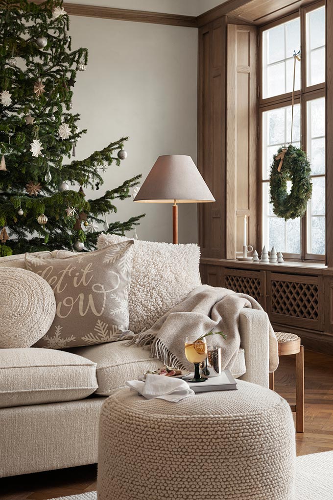 A stylish off white sitting room with a beautiful Christmas tree and wreath. Image: H&M Home.