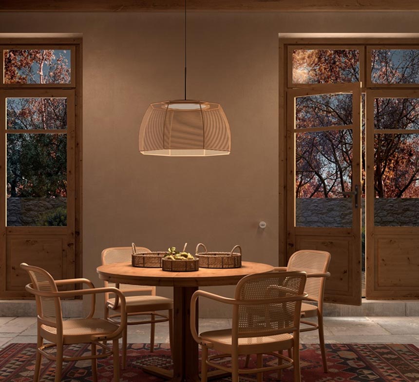 A dining space with an organic vibe, all in beige colors with a garden view after sunset hour, featuring the Tanit S/61 suspension light. Via: Nedgis.