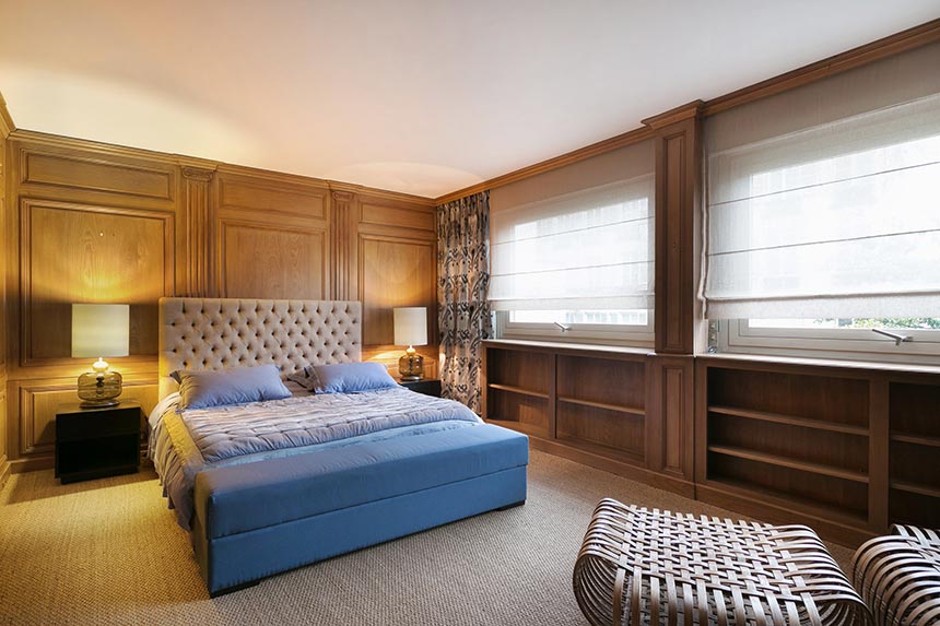 A stylish bedroom with wooden wall paneling from a Parisian apartment. Image: Boca do Lobo.