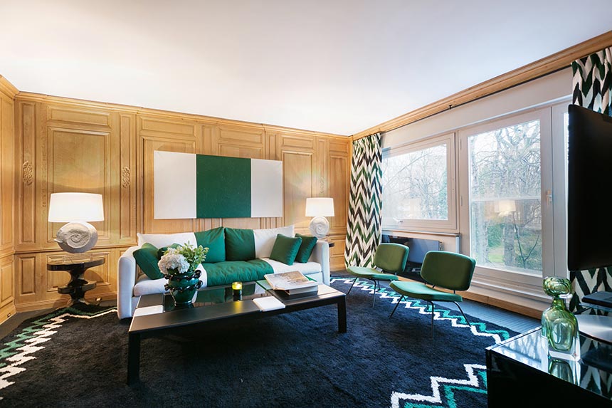 A stylish cinema room of a Parisian apartment featuring a white sofa, but lots of bold green accents. Image: Boca do Lobo.