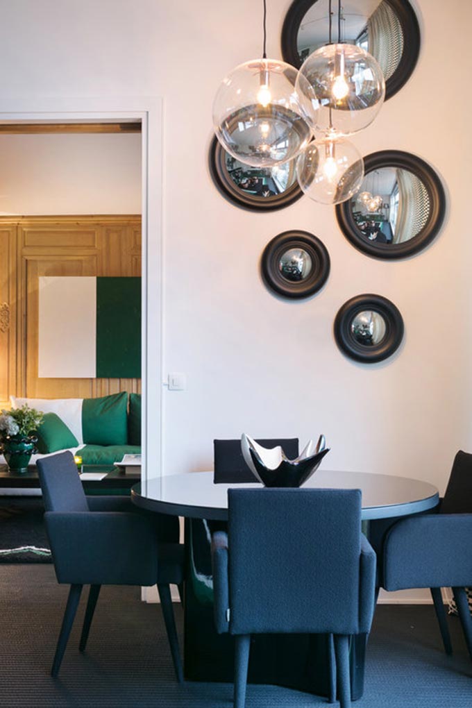 View of the dining room of a Parisian apartment with a round dining table featuring a glass pendant lighting fixture. Image: Boca do Lobo.