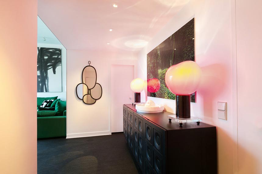Partial view of the entryway featuring a black credenza and two futuristic table lamps. Image: Boca do Lobo.