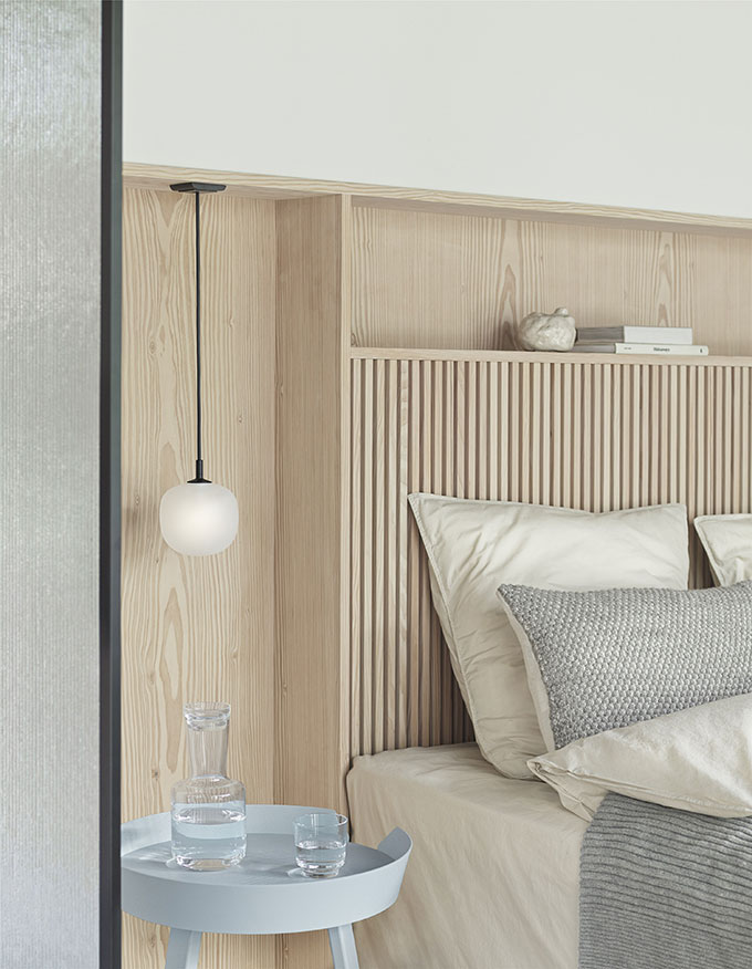 A Scandi minimal styled headboard with paneling, the Rime pendant light and a round side table. Image: Muuto.