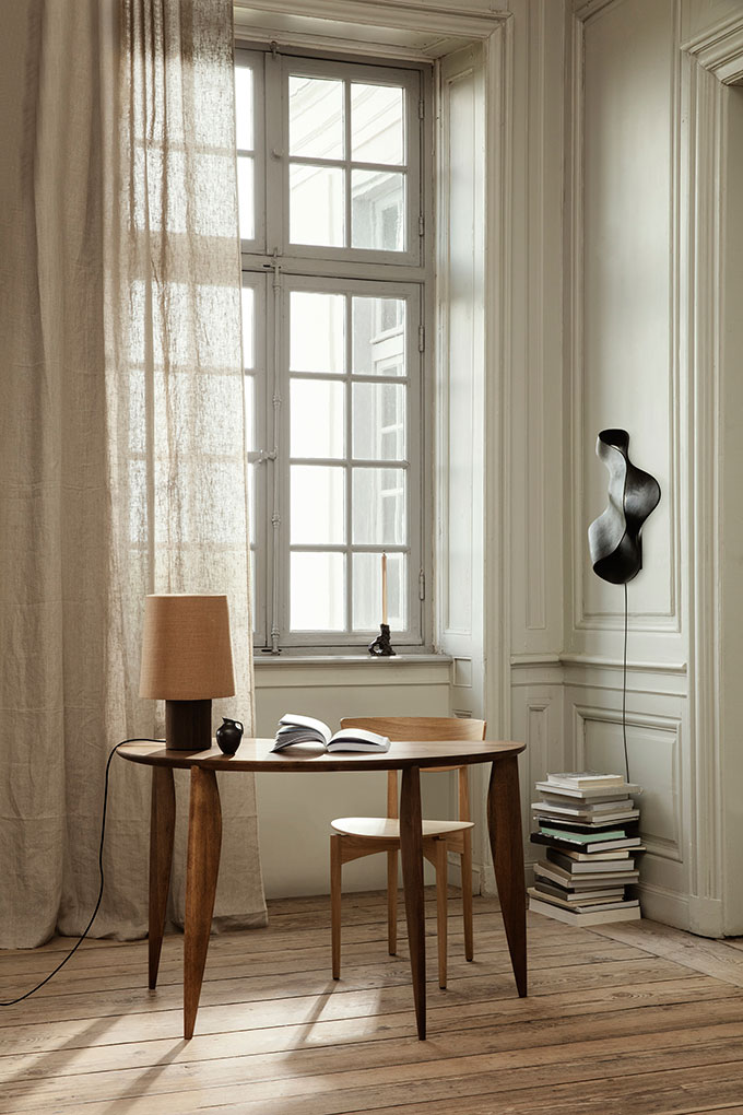 A corner home office with a large window in the background and the Feve desk in walnut. Scandi chic at its best. Image: fermLIVING.