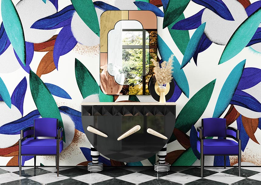 A brilliant bold, colorful print pattern wallpaper with a statement mirror and a black console table and two blue armchairs on either side of it. Image: Hommes Studio.