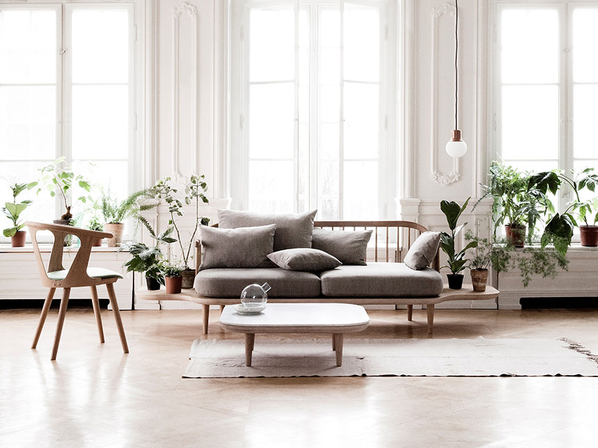 A contemporary neutral toned sitting room in front of open window doors. The sofa featured is the Design Sofa Fly SC3 from &Tradition. Image: HolzDesignPur.