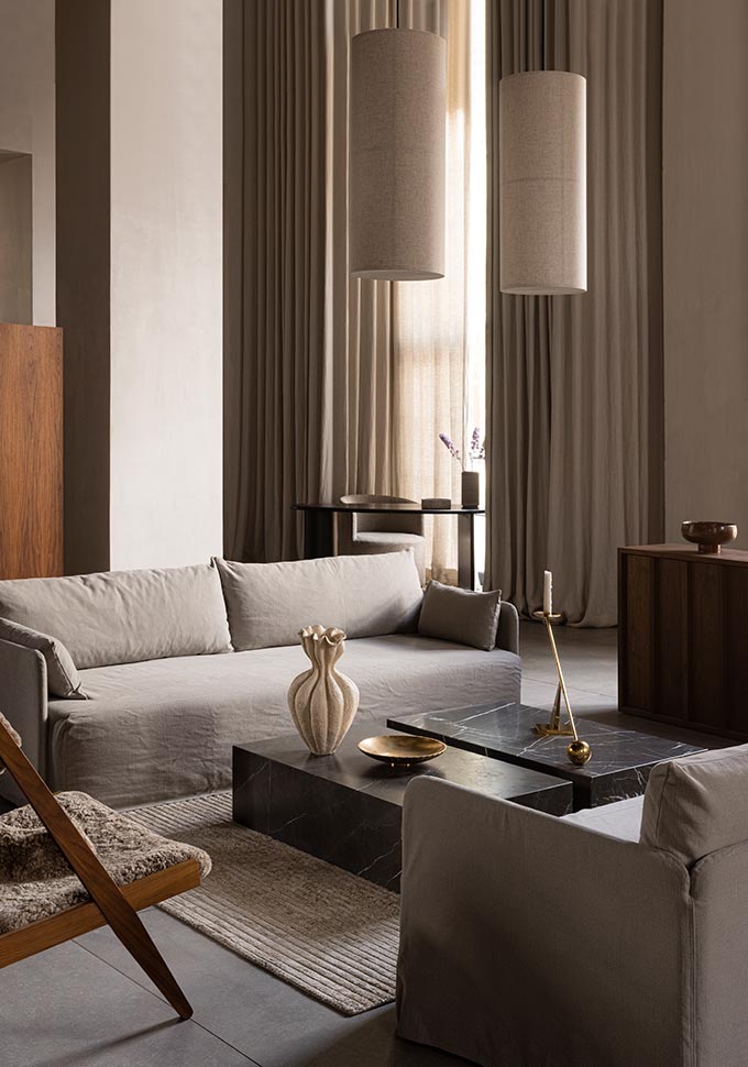 A lifestyle image of a beige toned contemporary sitting room featuring two Plinth Coffee Tables in black, side by side. Image: MENU.