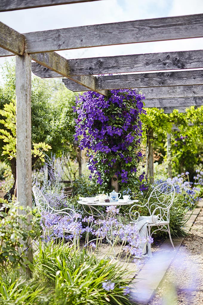 A metal garden set under a worn timber canapy at a wild garden. Such a beautiful setting. Image: OKA UK.