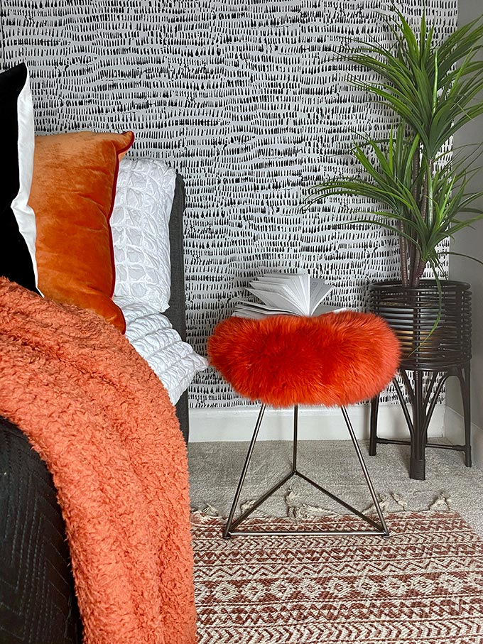 A lifestyle image of a bedroom loaded with different textures on the bedding and featuring a bright orange BAA stool. Image: Baa stool.