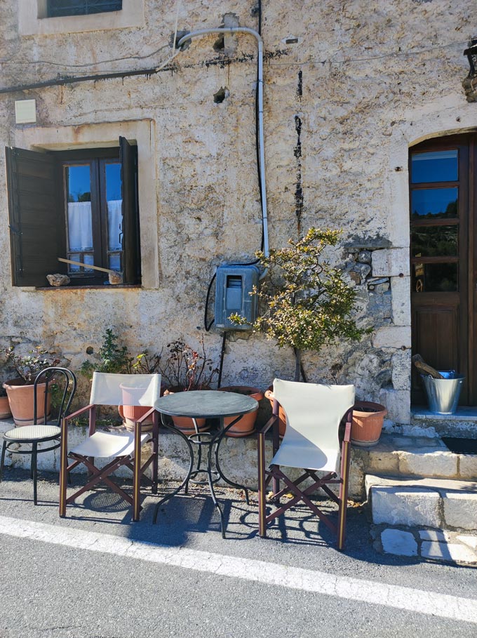 Directors chairs and table set up literally on the street outside a traditional stone house.