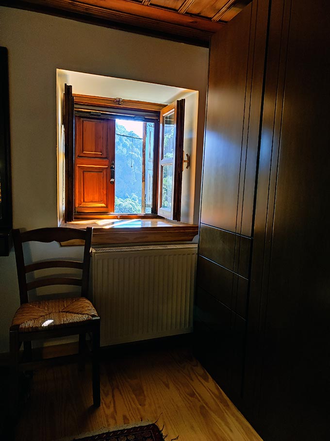 View of a window from inside a traditional house with thick walls and wooden finishes.