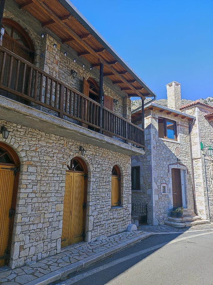 Two house facades made of stone along the street.