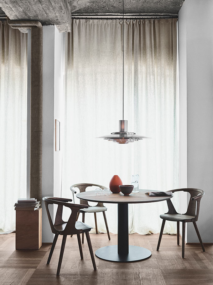 A dining space with an industrial vibe situated by an opening covered by a curtain panel. Window treatments work even in industrial spaces. Image: Nest.co.uk.