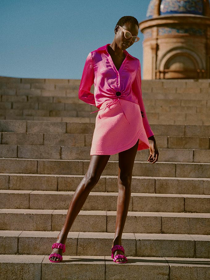 A lifestyle image of a woman dressed in a bright pink spring outfit. Image: River Island.