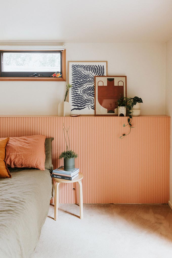 A warm toned minimal Scandi boho bedroom with beautiful small pots and ridged coral wall ridged panelling. Image: Capra designs.