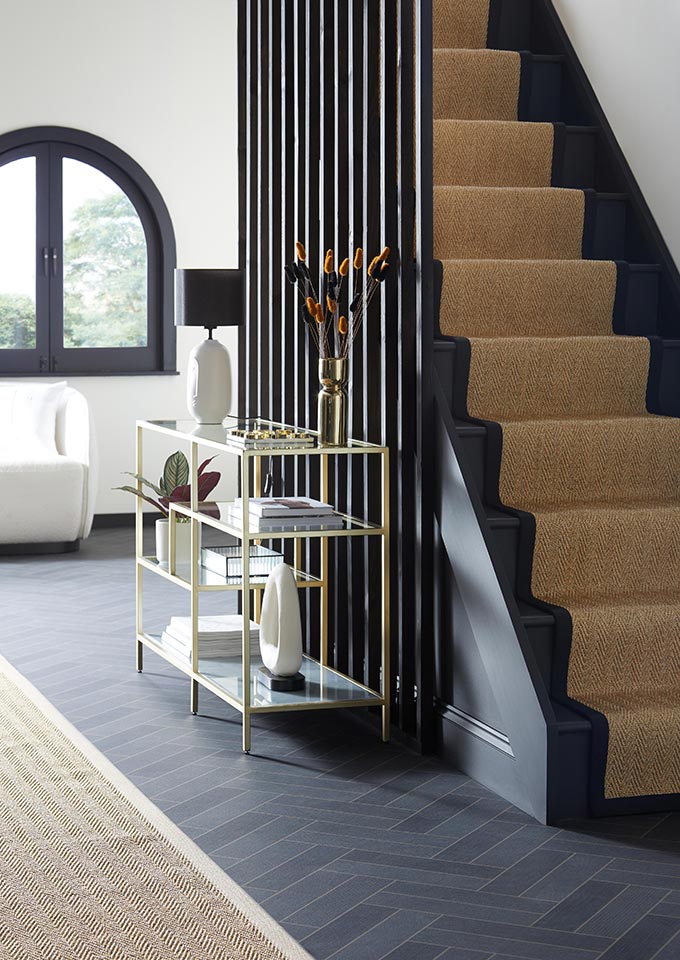 An off black staircase with black ridged cladding and a jute runner. Image: Dunelm.