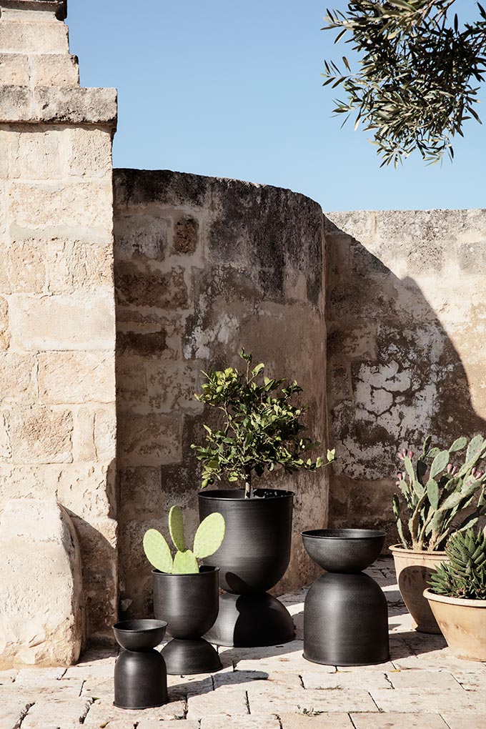 A lifestyle image of several hourglass pots from fermLIVING in front of a stone wall. Image: fermLIVING.