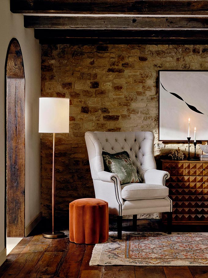 Beauty is a must for a happy home. A lifestyle image of the Porter armchair next to a textured wooden credenza in front of an exposed brick wall. Image: Soho House.