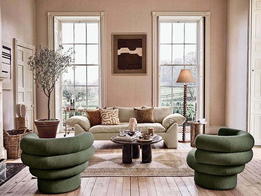 Just love this sitting room setup with muted earth colors, curvy green armchairs, round brown veined marble coffee table and soft beige sofa. Image: Soho House.