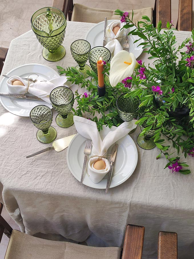 A bird's eye view of an Easter tablescape with an organic vibe and lots of greenery stretched across the table.