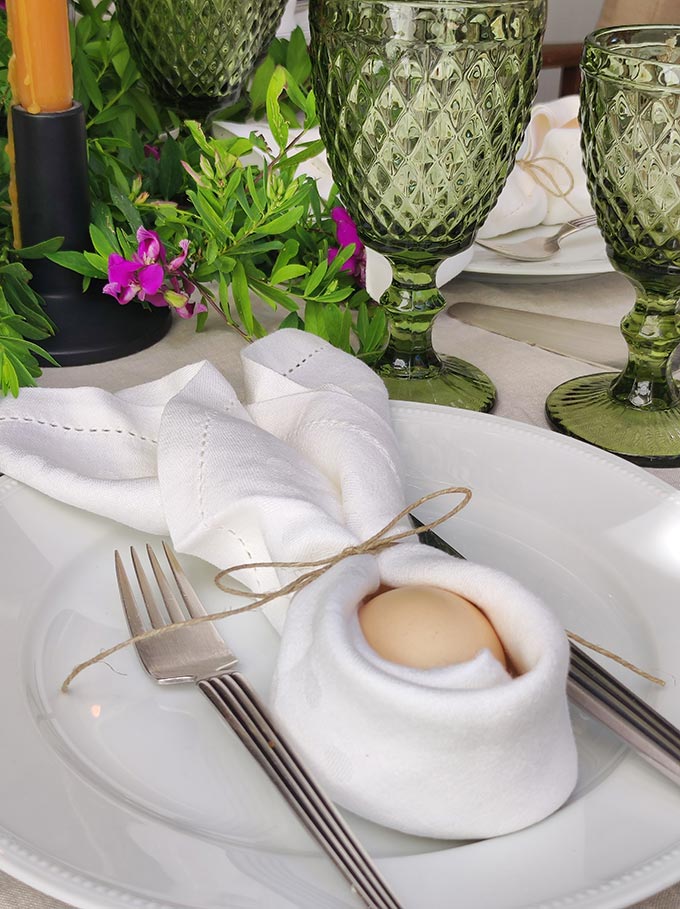 A closer view of an egg dressed as a bunny with the help of a linen napkin for the sake of an Easter luch tablescape.