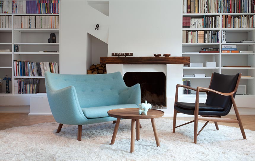 A sitting room with built-in bookcases in the background and Scandinavian design sofa, armchair and the Pelican Table from House of Finn Juhl. Image: Nest.co.uk.