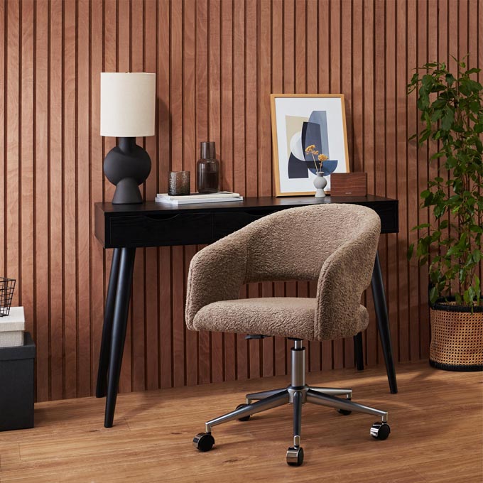 Brown tones - one of the interior design trends for 2023. A ribbed wall panel in a warm wood tone with a dark desk against it and a swivel desk chair in a taupe boucle upholstery fabric. Image: Cult Furniture.