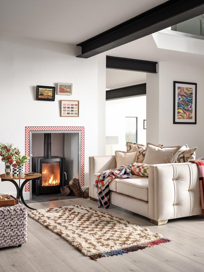 A white sitting room with a fireplace and colorful decor with various print patterns. Image: Sofology.