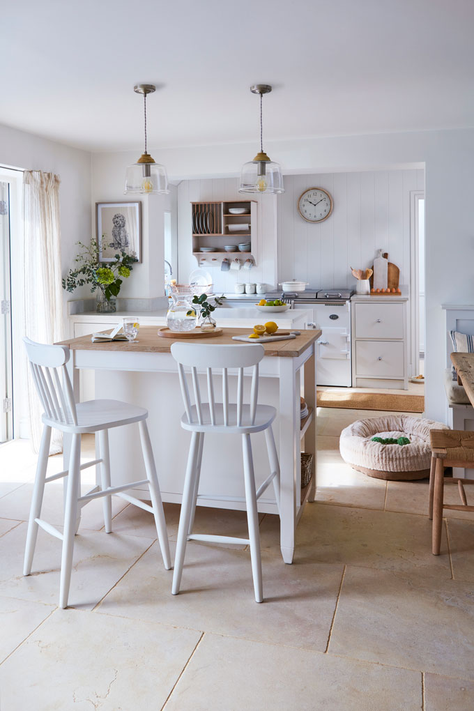 A white charming Farmhouse inspired kitchen with a small kitchen island, open shelving and shiplap paneling.