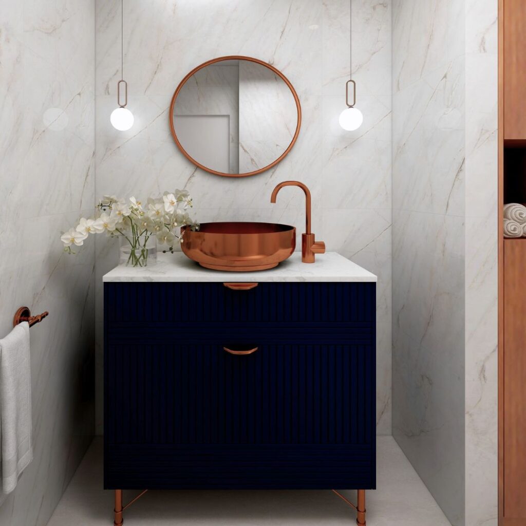 A powder room with a rose gold basin, tap, white marble with copper veins wall cladding, hanging pendants and a dark navy vanity. Image copyright: Velvet Karatzas IDA.